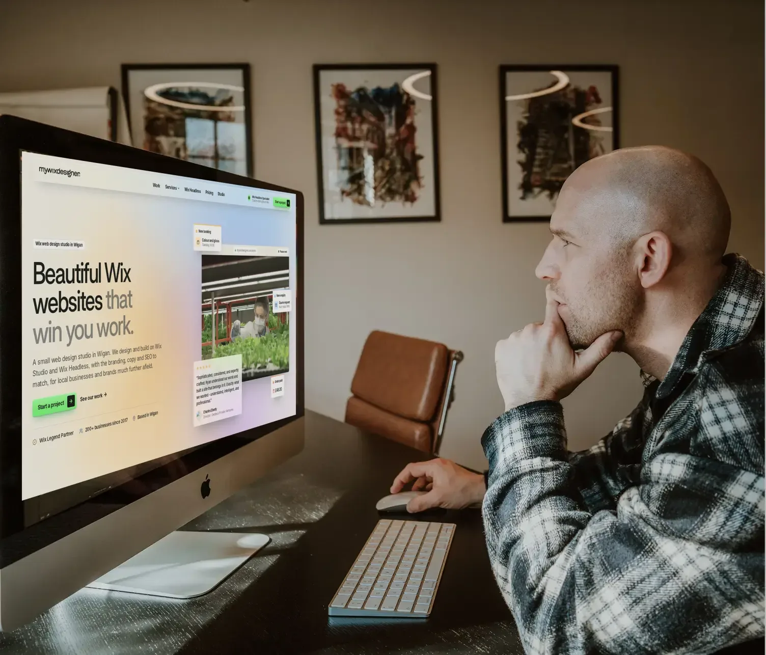 Ryan at his desk in the studio, with a website design on screen